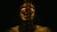 A dark scene where a person is slightly visible in the background with a film strip displaying the word 'FIN' multiple times vertically. The person appears to have tattoos on their shoulder.