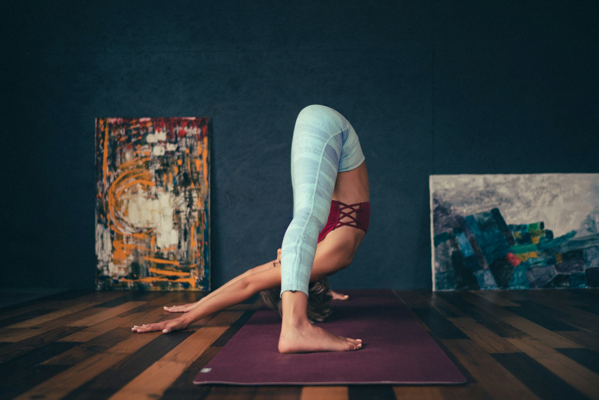 A flexible yogini doing a forward bend pose in an artistic interior. Photo by Oksana Taran.