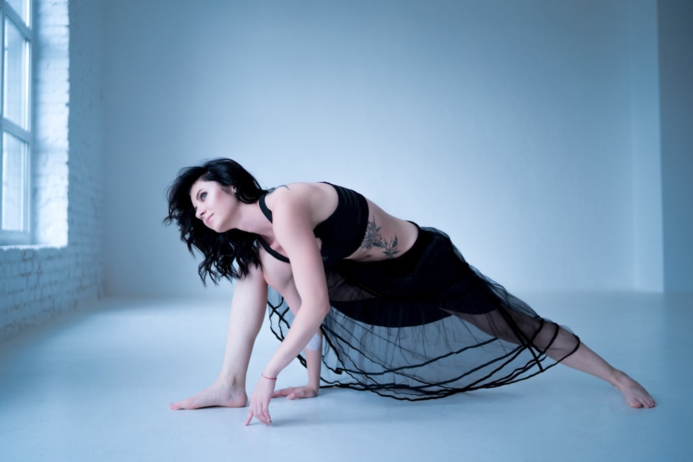 woman in black tank top and black and white skirt lying on blue floor