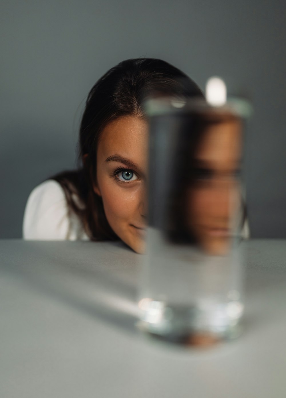 woman in white shirt holding clear glass cup