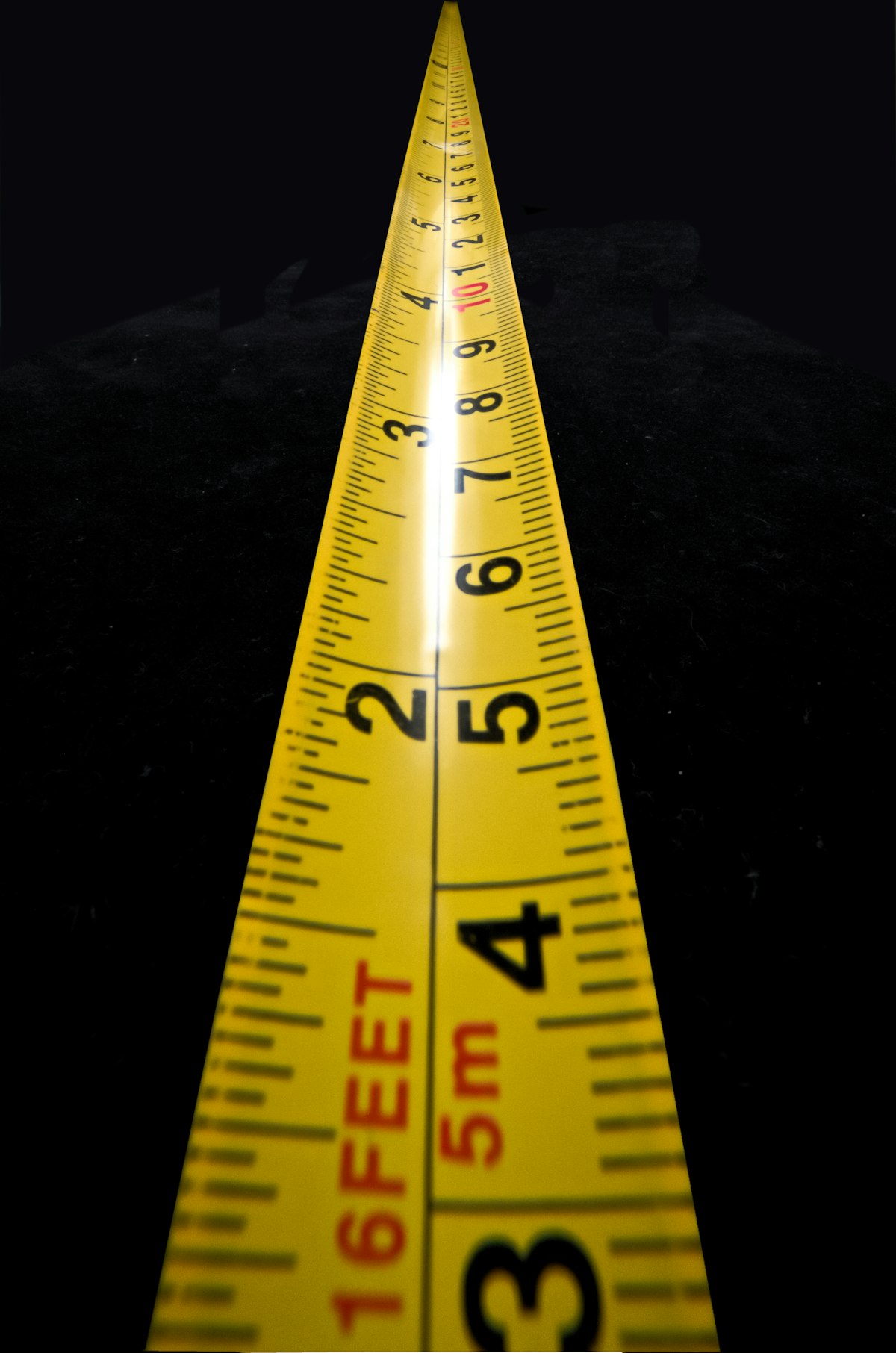 Yellow and black tape measure extended across a wall opening to check the size needed before buying a replacement louvre vent