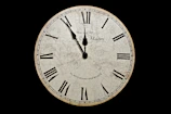 A vintage clock with its hands spinning backward against a dark background.