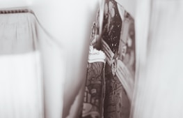 A close-up image highlighting the pages of a book that appears to be a comic or graphic novel. The focus is on a central page, while other pages are visible blurred in the background. The monochromatic tone adds an artistic and vintage feel.