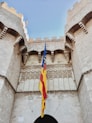 yellow blue and red flag on top of brown concrete building during daytime