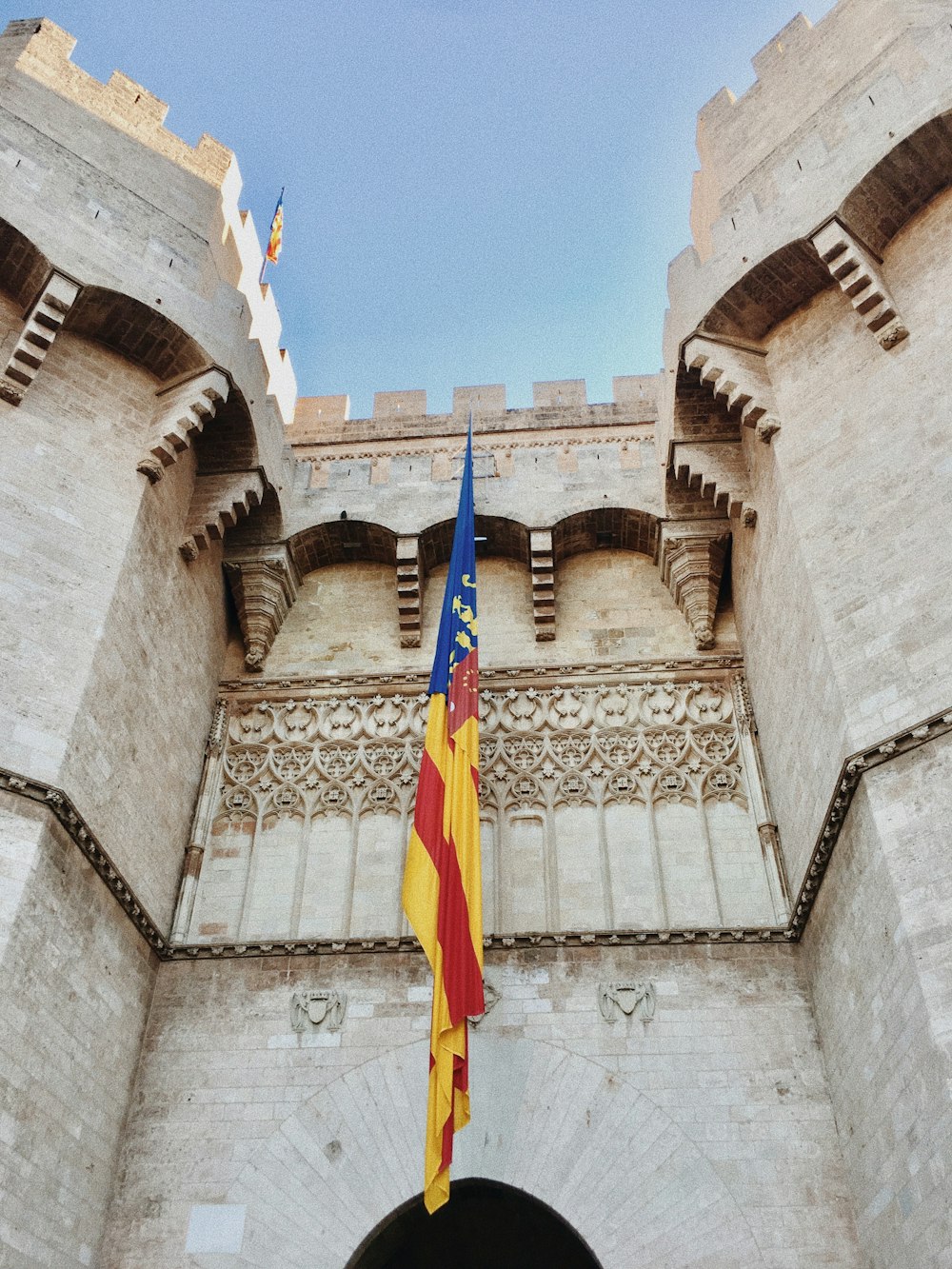 bandeira azul amarela e vermelha no topo do edifício de concreto marrom durante o dia