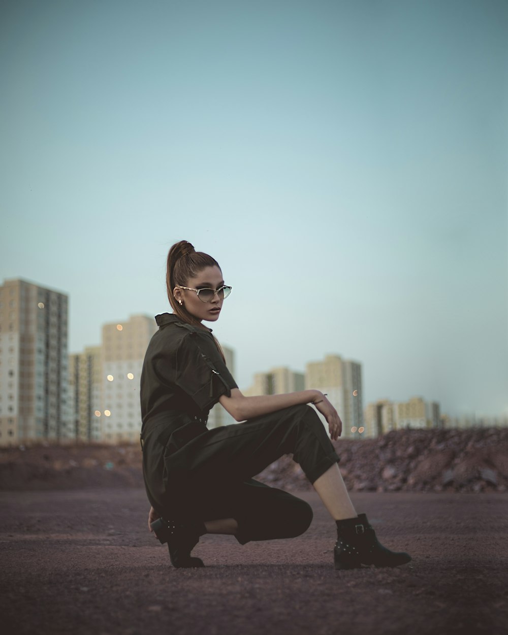 woman in black leather jacket and black pants sitting on brown concrete floor during daytime