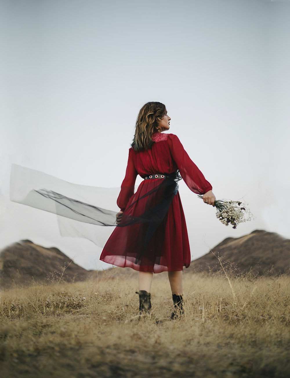 woman in red long sleeve dress standing on brown grass field during daytime