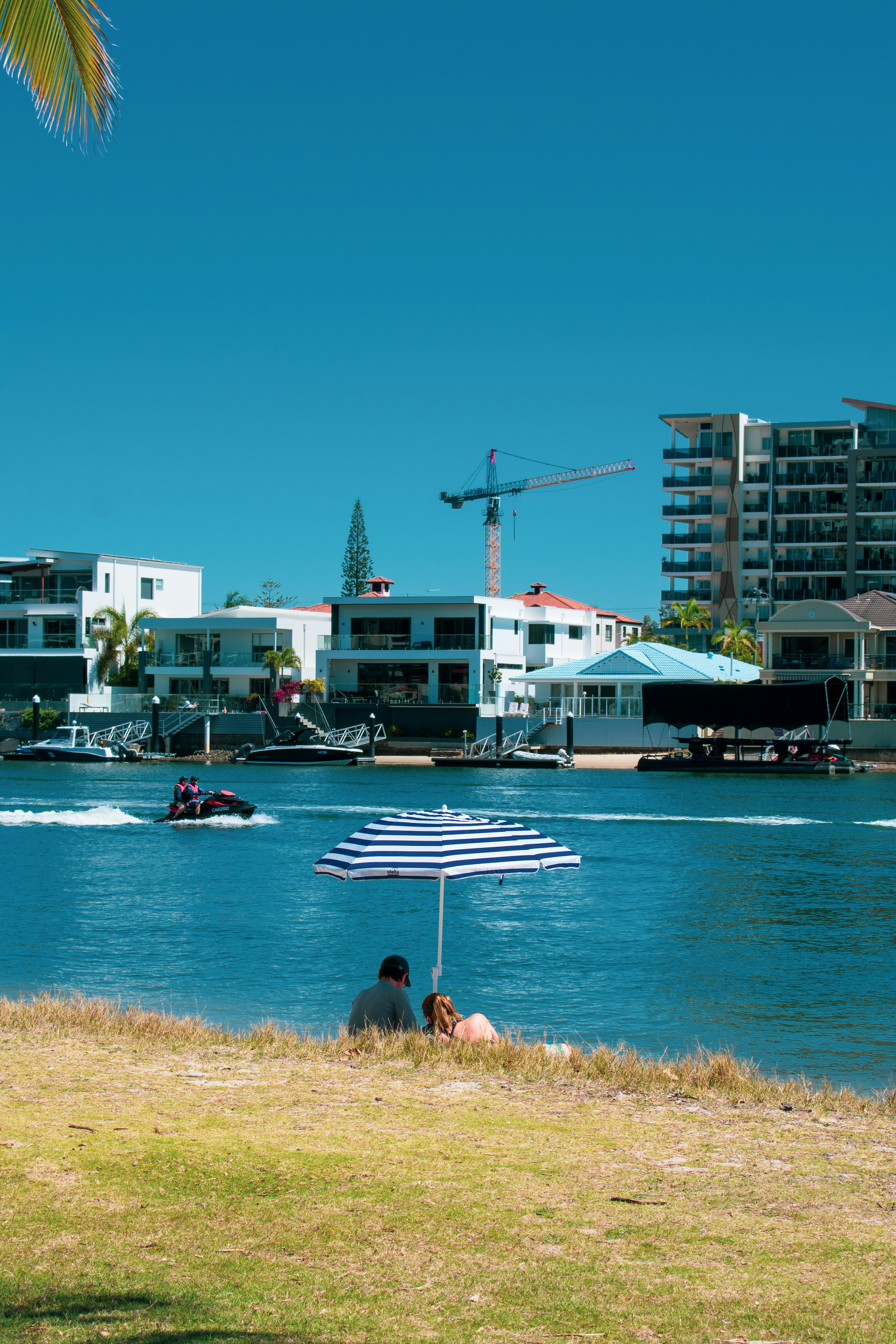 woman in red bikini sitting on brown sand near body of water during daytime