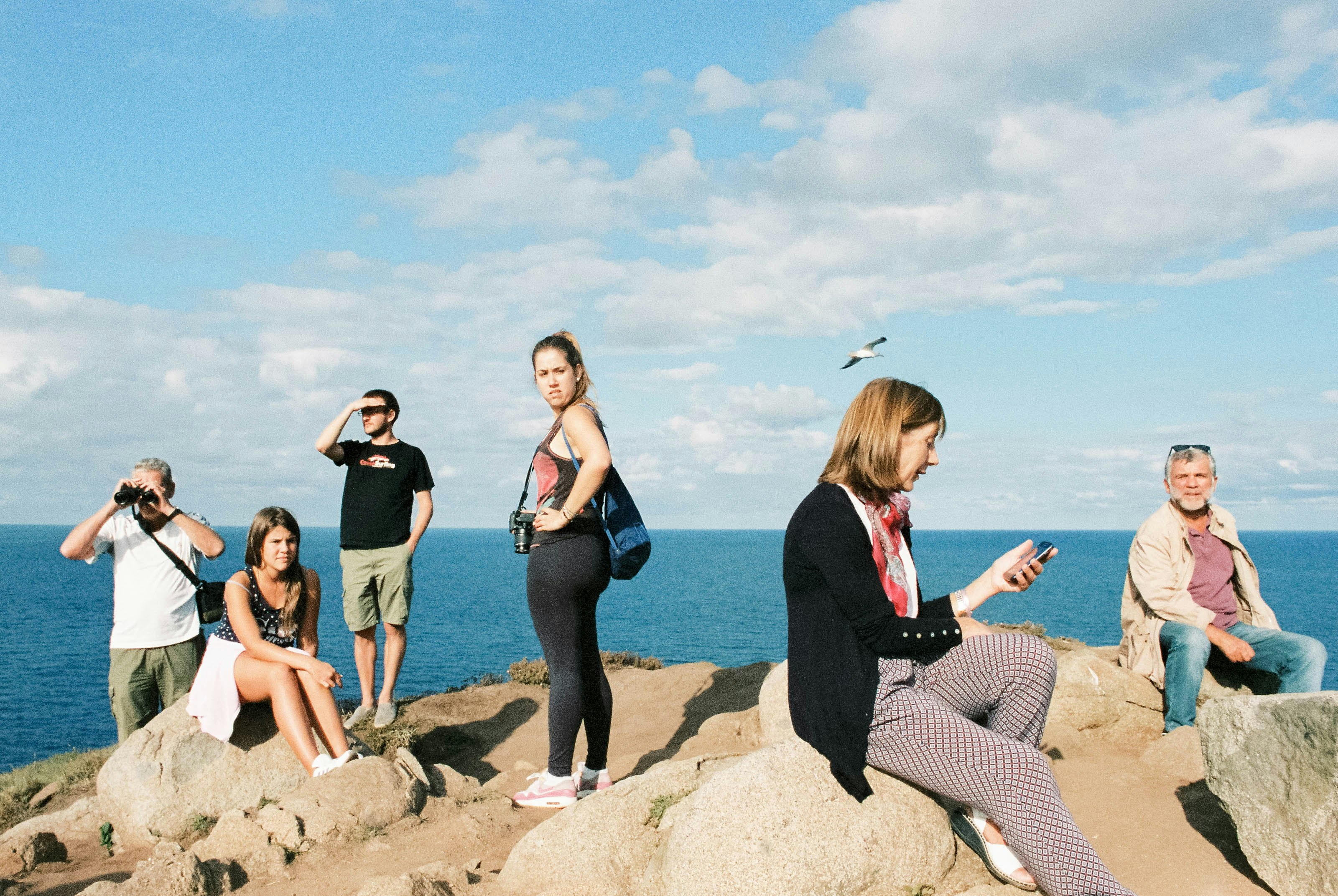 3 women sitting on rock near sea during daytime