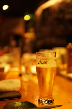 Close-up of a frothy beer glass on a wooden table inside a classic Angers brasserie.