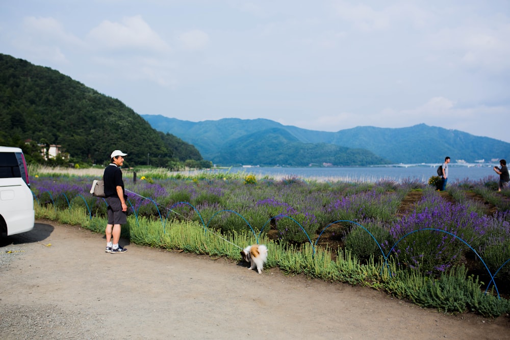 man in black t-shirt and black shorts walking with dog on pathway during daytime