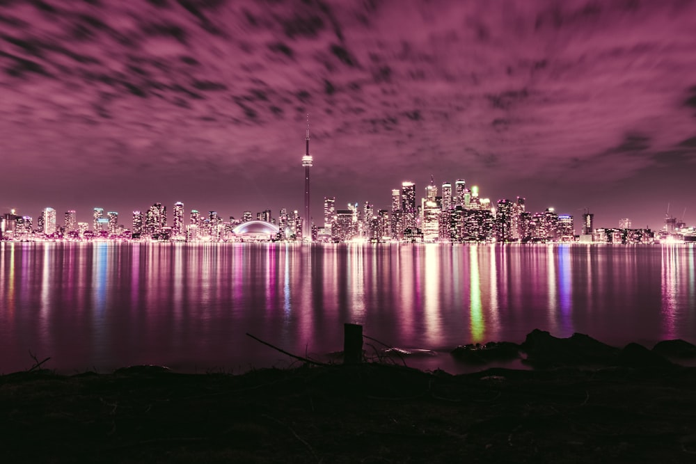 city skyline across body of water during night time