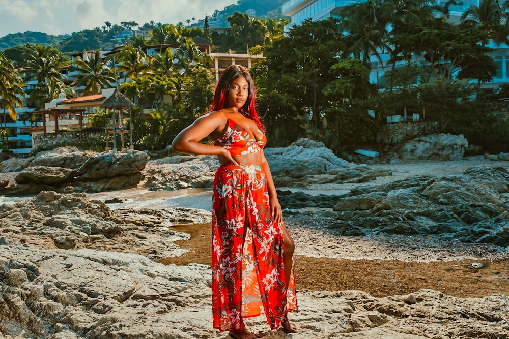 woman in red and white floral dress standing on beach during daytime