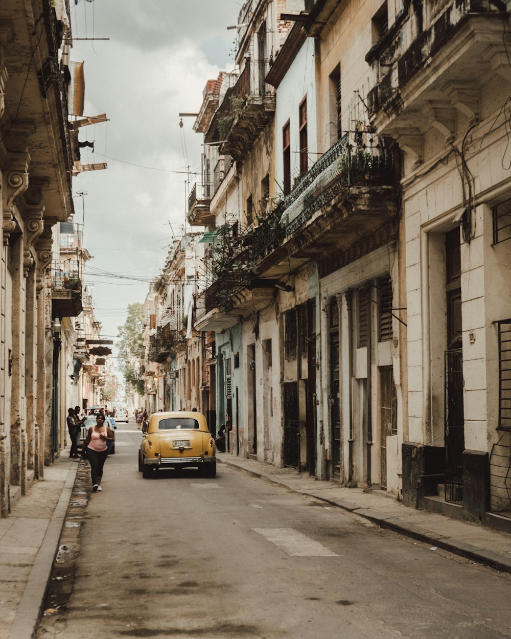 yellow car on road between buildings during daytime