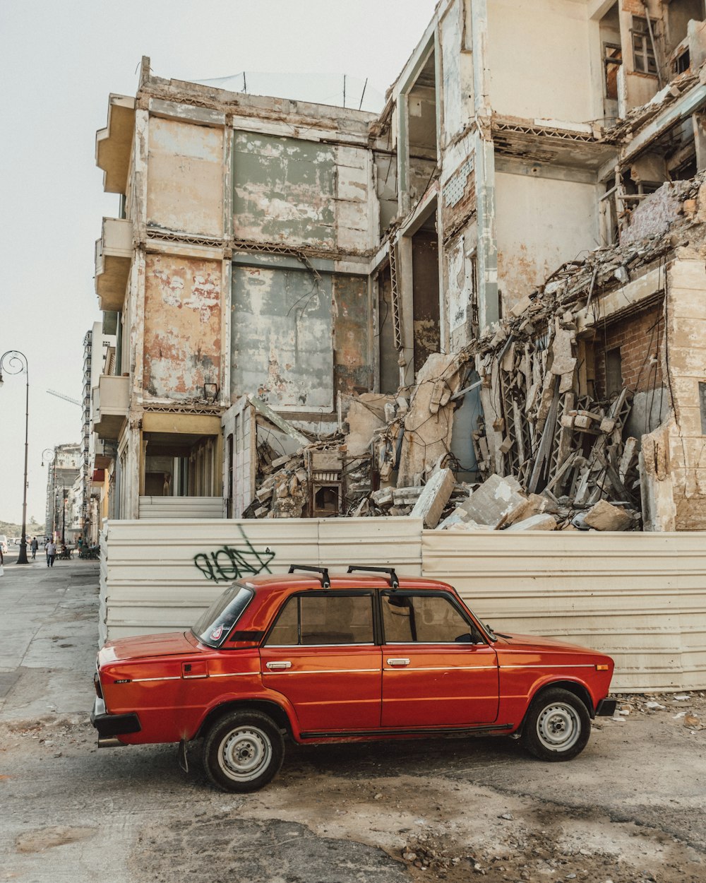 red car parked beside building during daytime