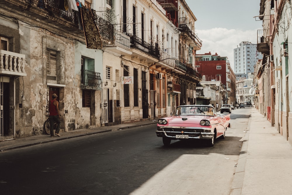 red and white sedan on road near buildings during daytime