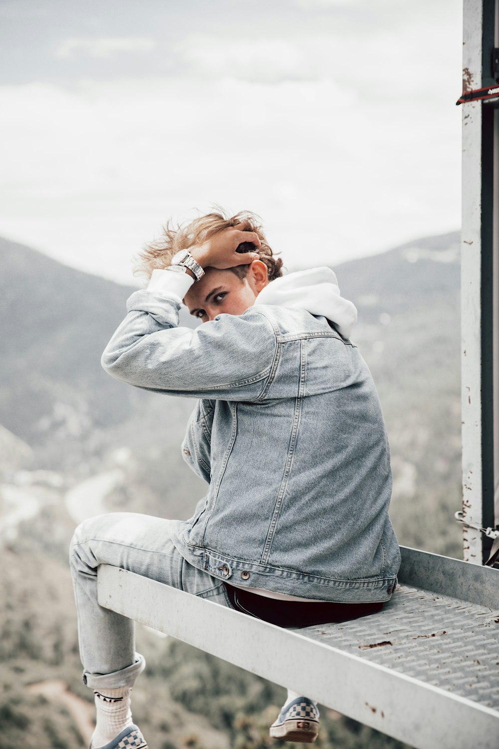 woman in gray hoodie leaning on gray wooden fence during daytime