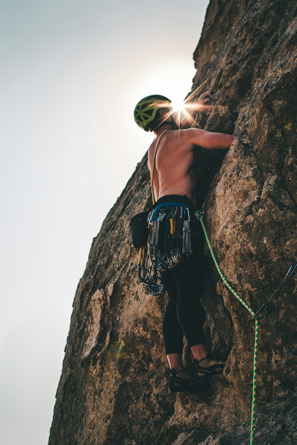 man in blue shorts climbing on brown rock during daytime