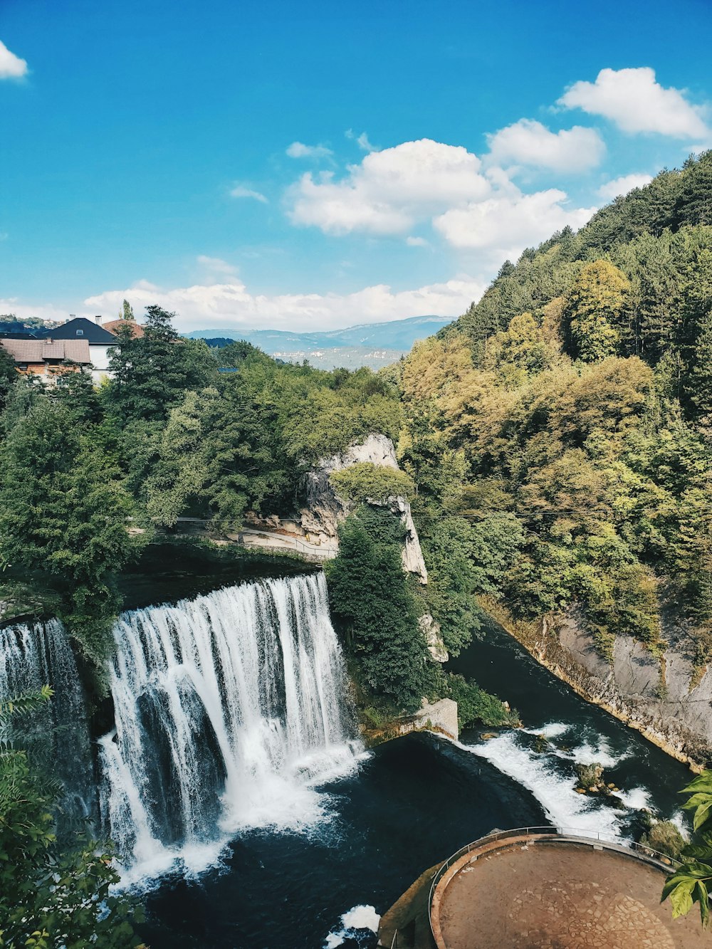 昼間の青空の下、緑の木々のそばの滝