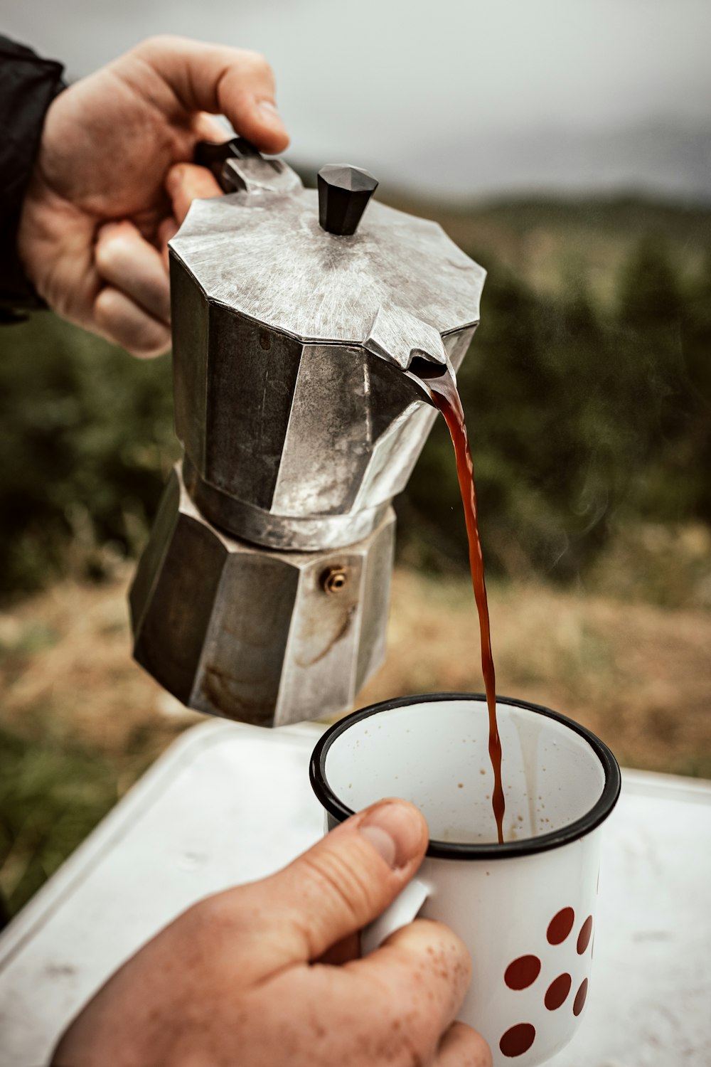 person pouring red liquid on silver and black teapot