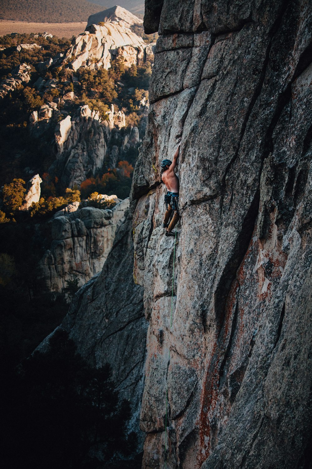 woman in black tank top climbing on gray rocky mountain during daytime