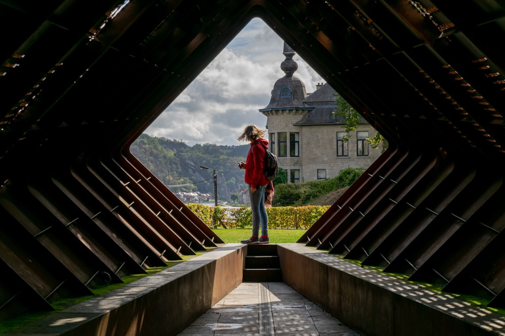 man in red long sleeve shirt standing on brown wooden bridge during daytime