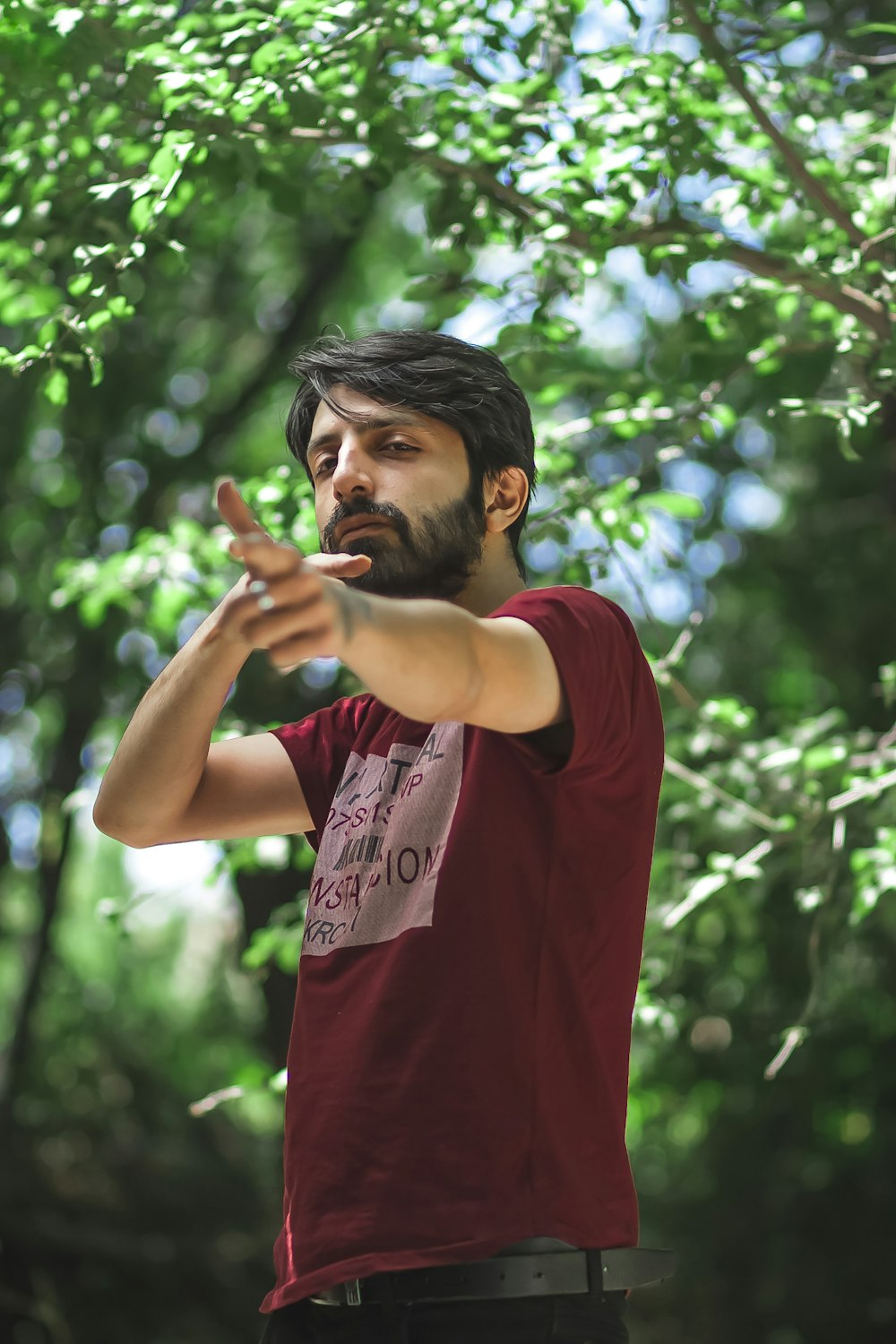 man in red crew neck t-shirt standing near green trees during daytime