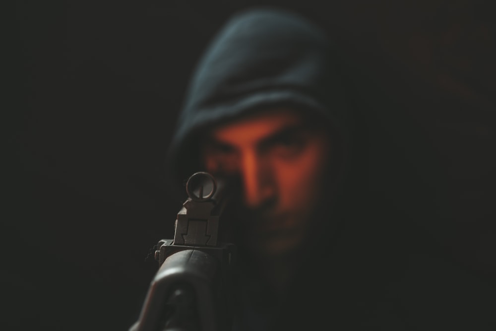 man in black hoodie holding black rifle