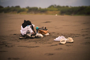 A collection of clothing pieces organized on a sandy shore.