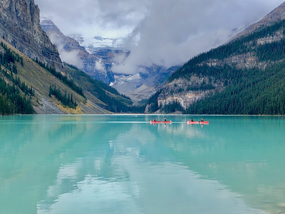 green lake near green mountains under white clouds during daytime