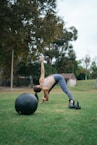 woman in white tank top and gray leggings doing push up on black exercise ball on near near near near