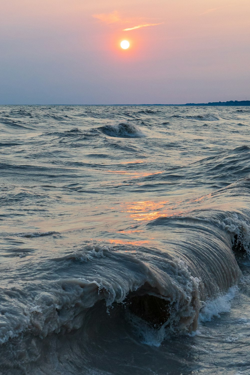 Meereswellen stürzen während des Sonnenuntergangs an Land