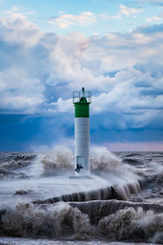 A calm lighthouse standing firm against a stormy sea under a gray sky, symbolizing steadiness amidst uncertainty.