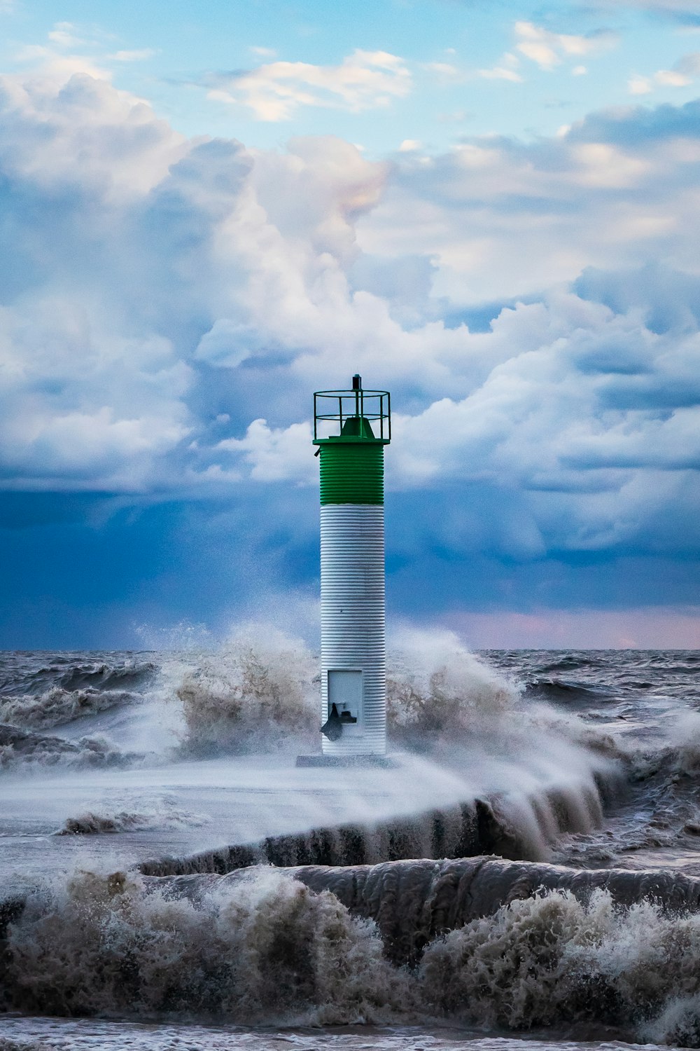 white and green lighthouse on white clouds during daytime