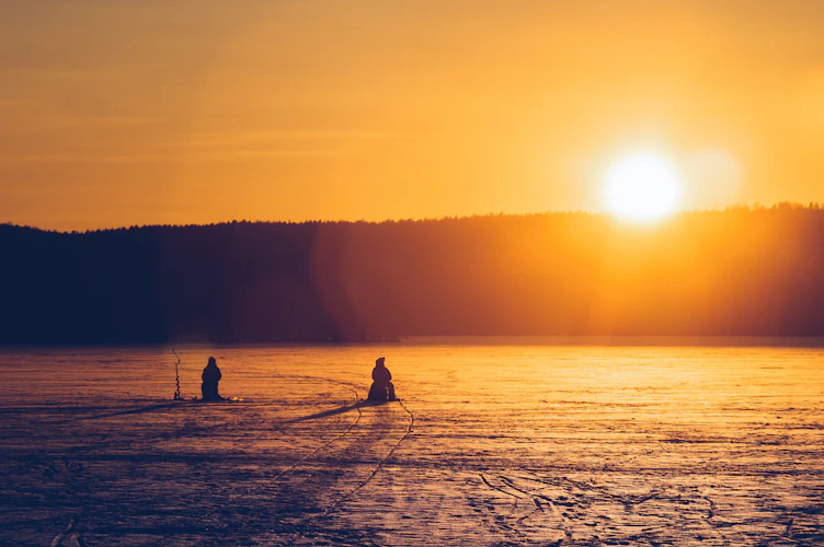 ice fishermen at sunset on a frozen Colorado lake