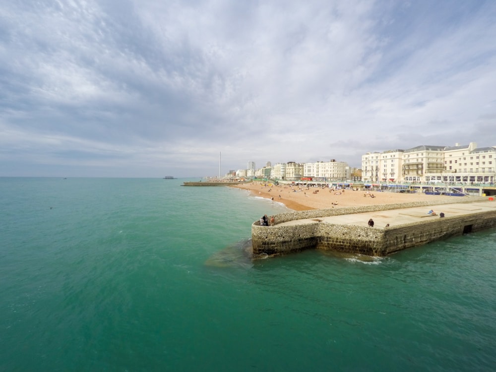 edificio in cemento bianco vicino a uno specchio d'acqua durante il giorno