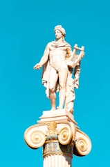 A glowing lyre resting on a marble column with soundwaves gently radiating around it against a deep navy background.