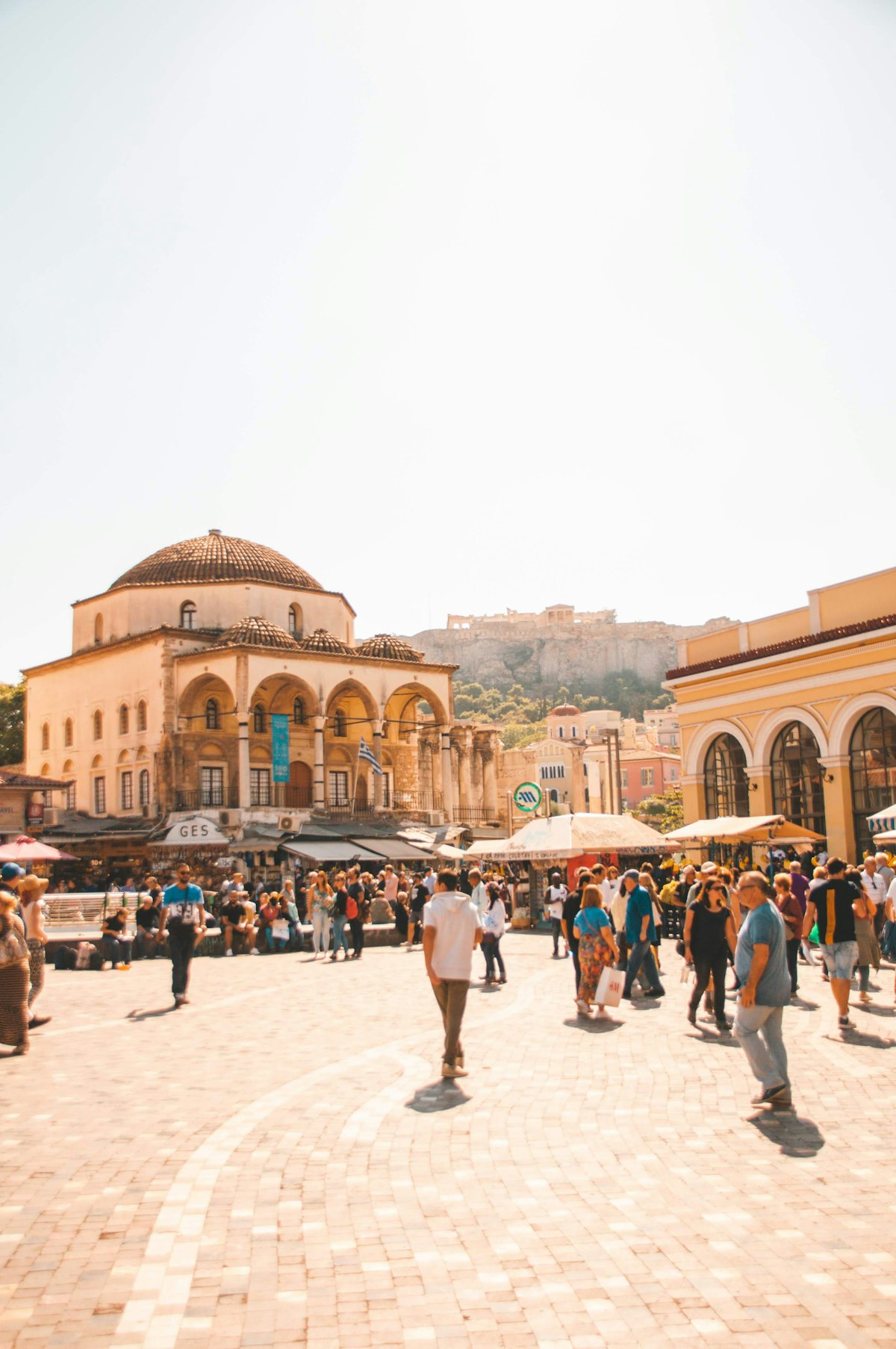 Monastiraki Athens — Monastiraki Square with the domed Tzistarakis Mosque, crowds at the flea market and the Acropolis hill behind