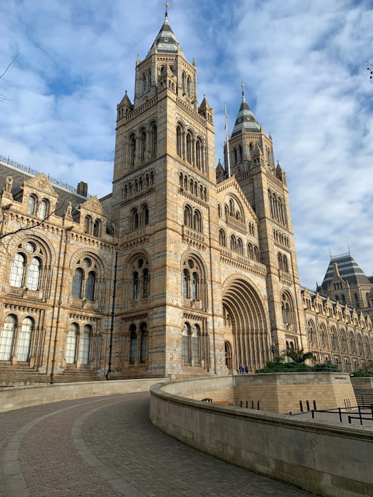 brown concrete building under white clouds during daytime in Natural History Museum United Kingdom