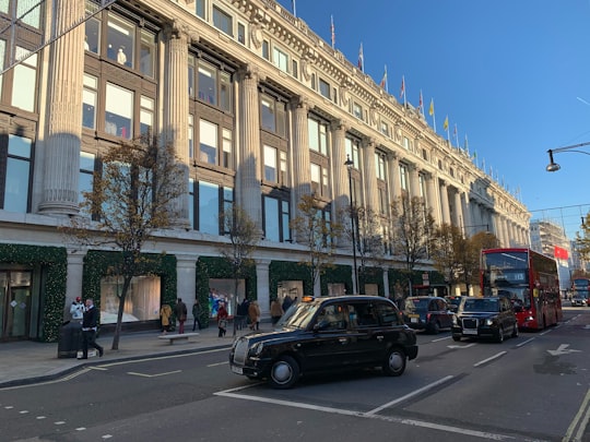 cars parked in front of beige concrete building during daytime in Oxford Street United Kingdom