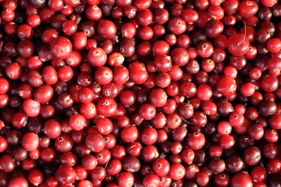 red round fruits on white surface cranberry teams background
