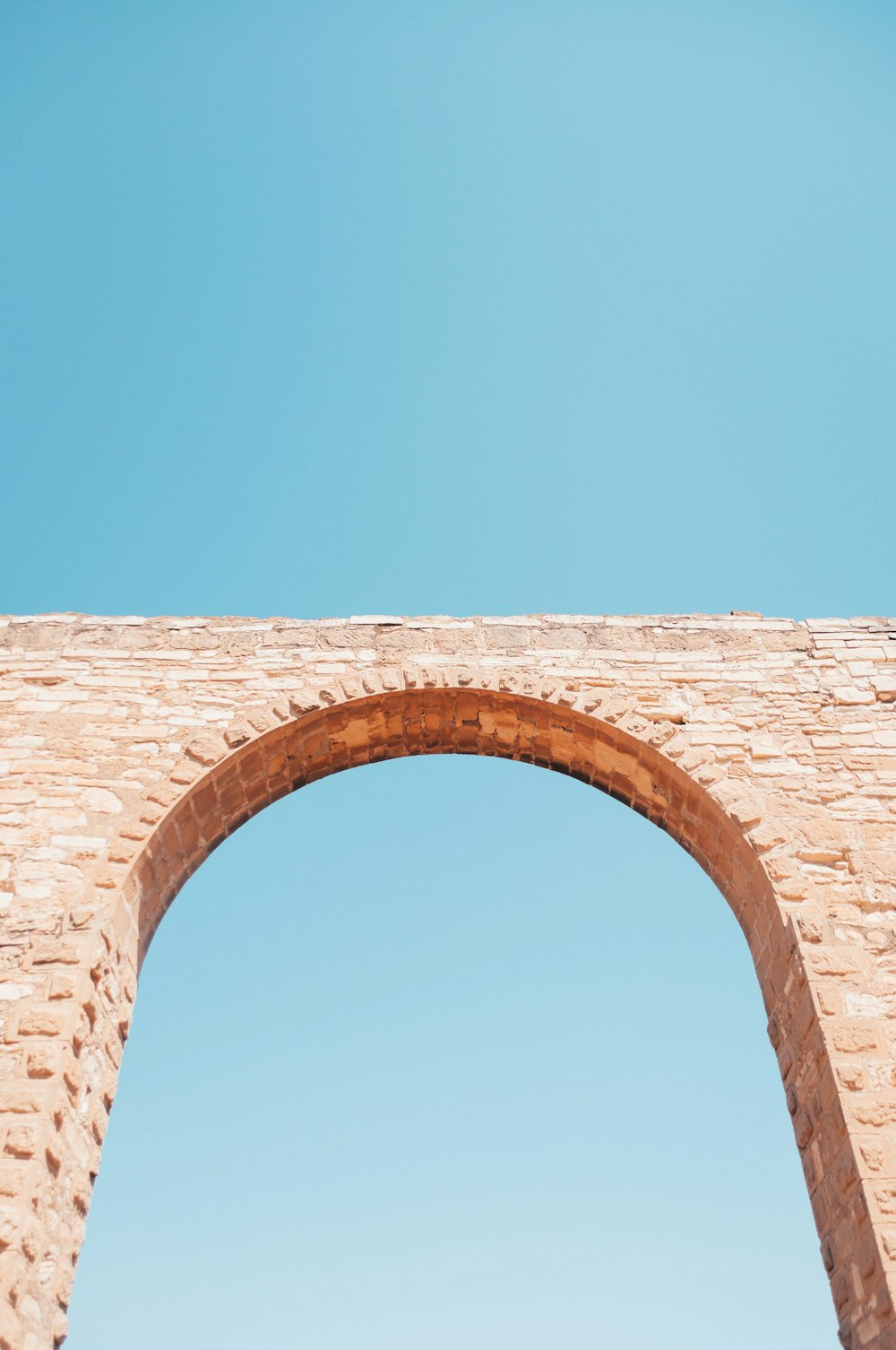 brown brick arch under blue sky during daytime