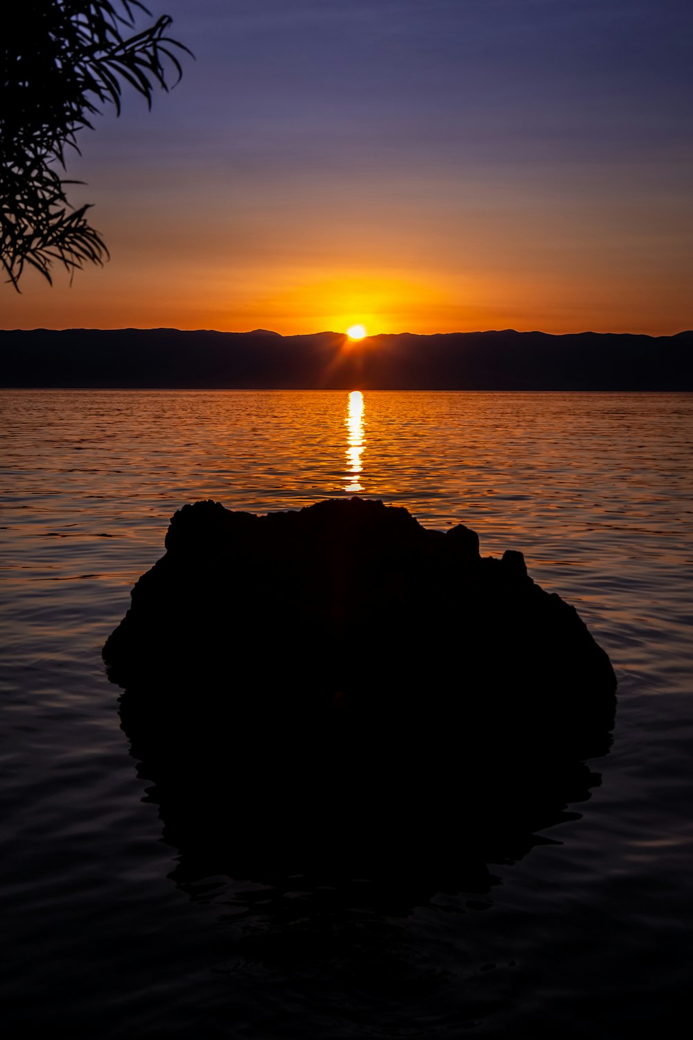 Silueta de roca en el agua durante la puesta del sol