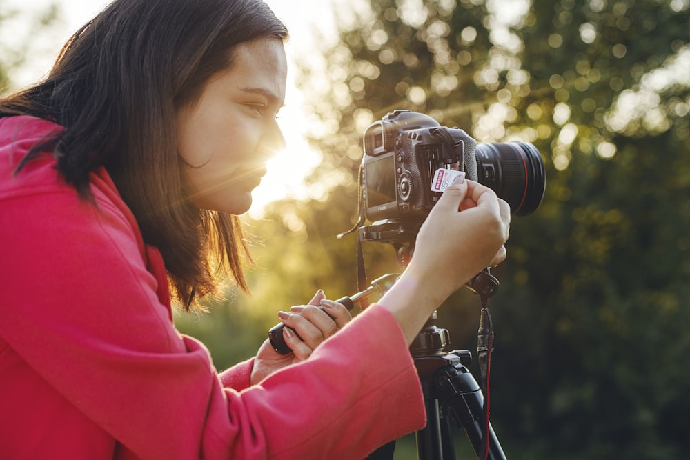 검은 DSLR 카메라를 들고 빨간 재킷을 입은 여자