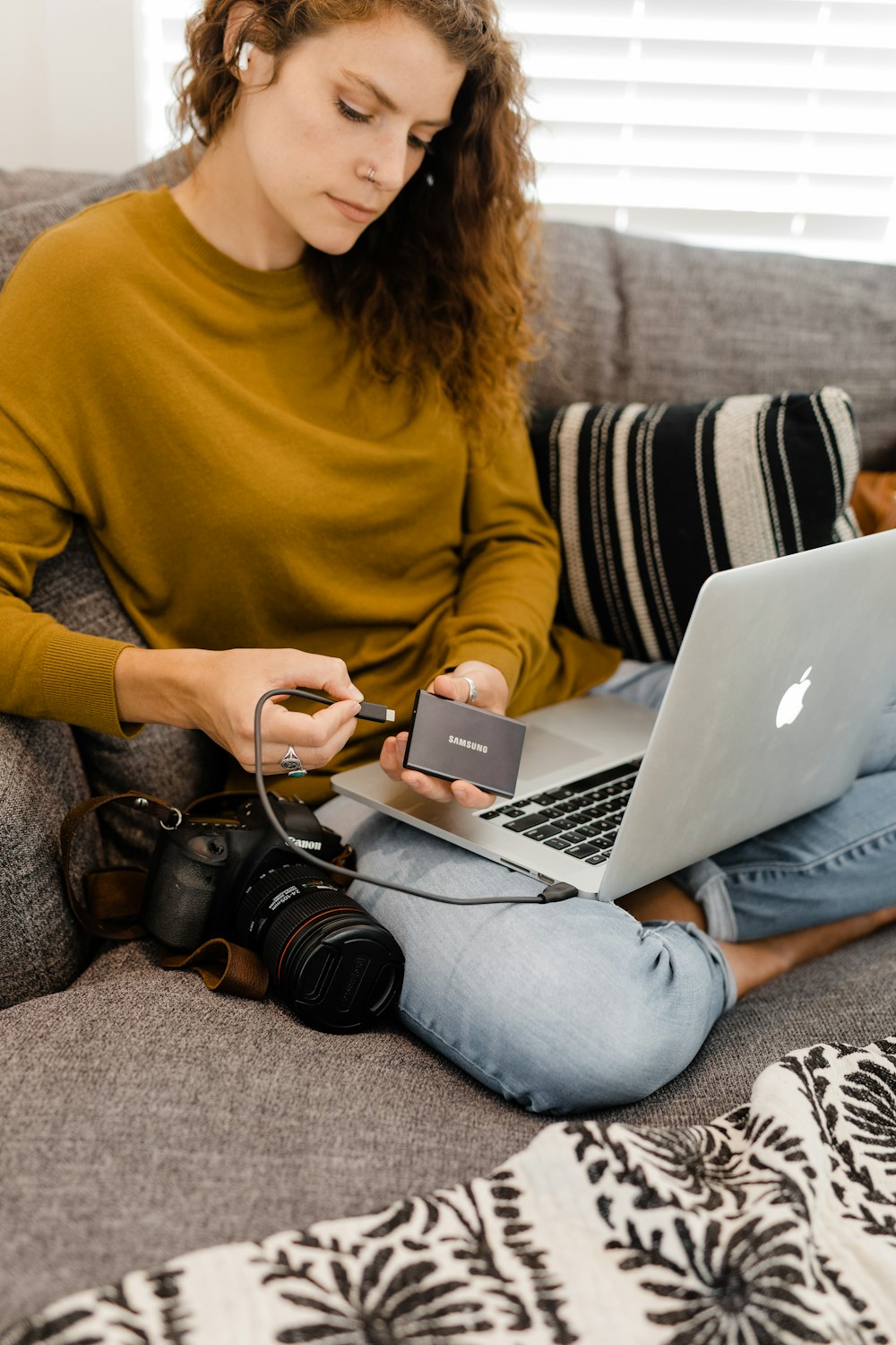 mulher no suéter amarelo usando macbook de prata