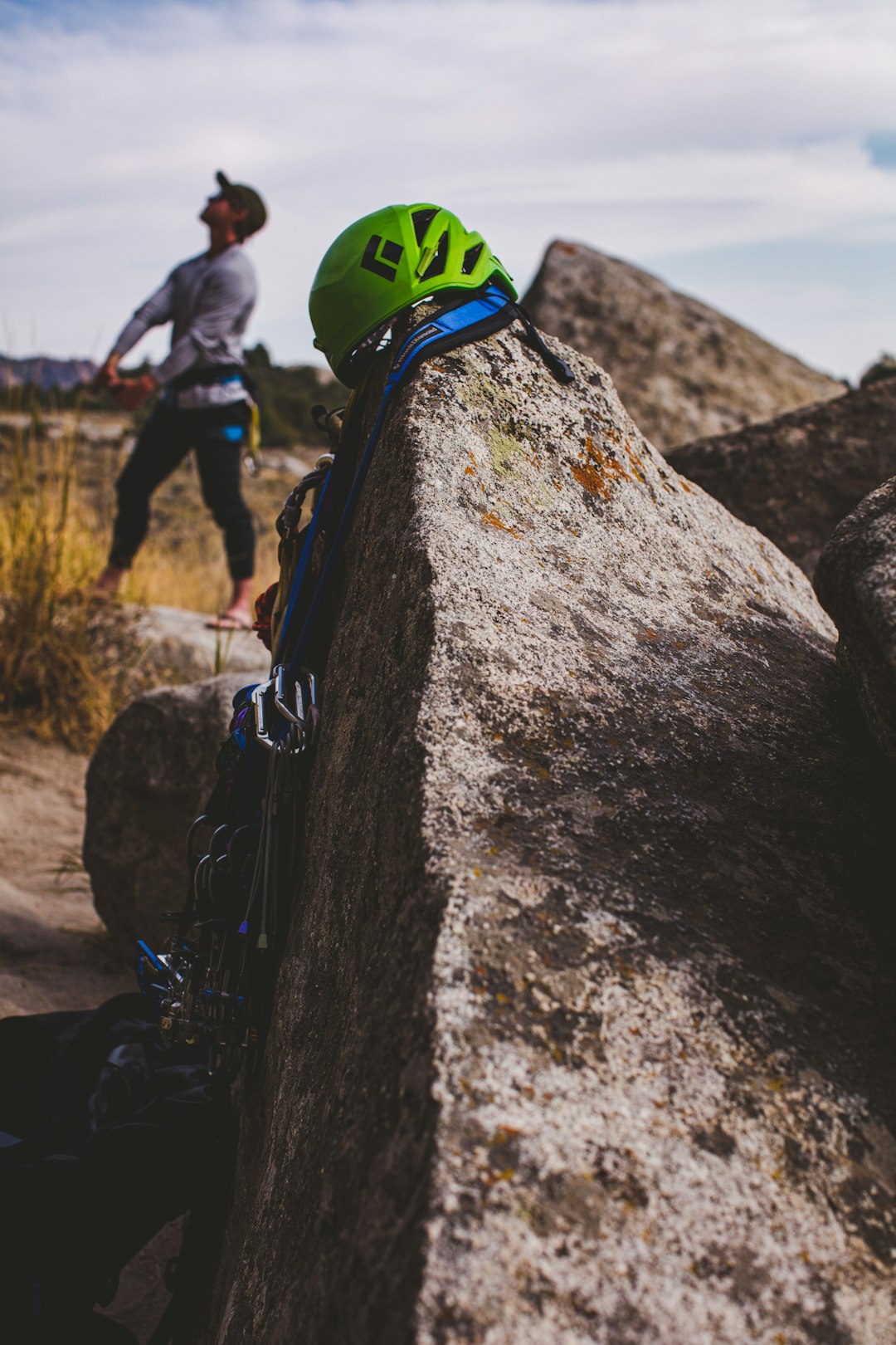 man in green and black helmet climbing on gray rock during daytime