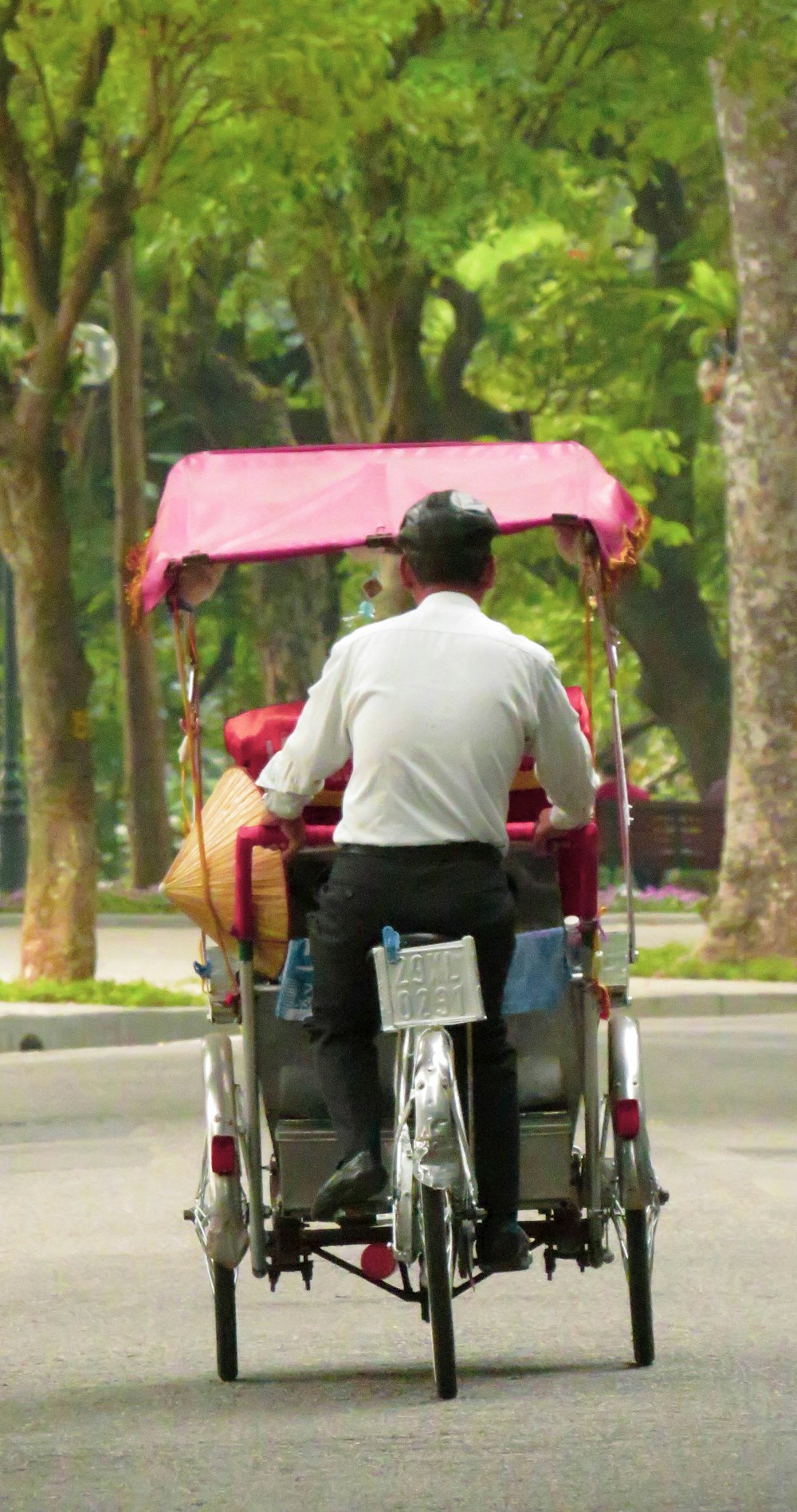 man in white dress shirt riding on red and white trike during daytime