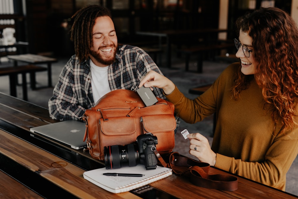 man in black and white plaid dress shirt holding black dslr camera