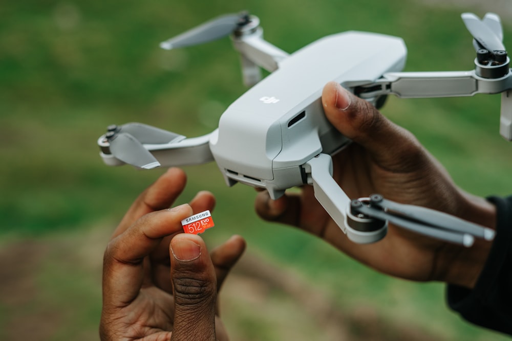 person holding white drone with red and white cards