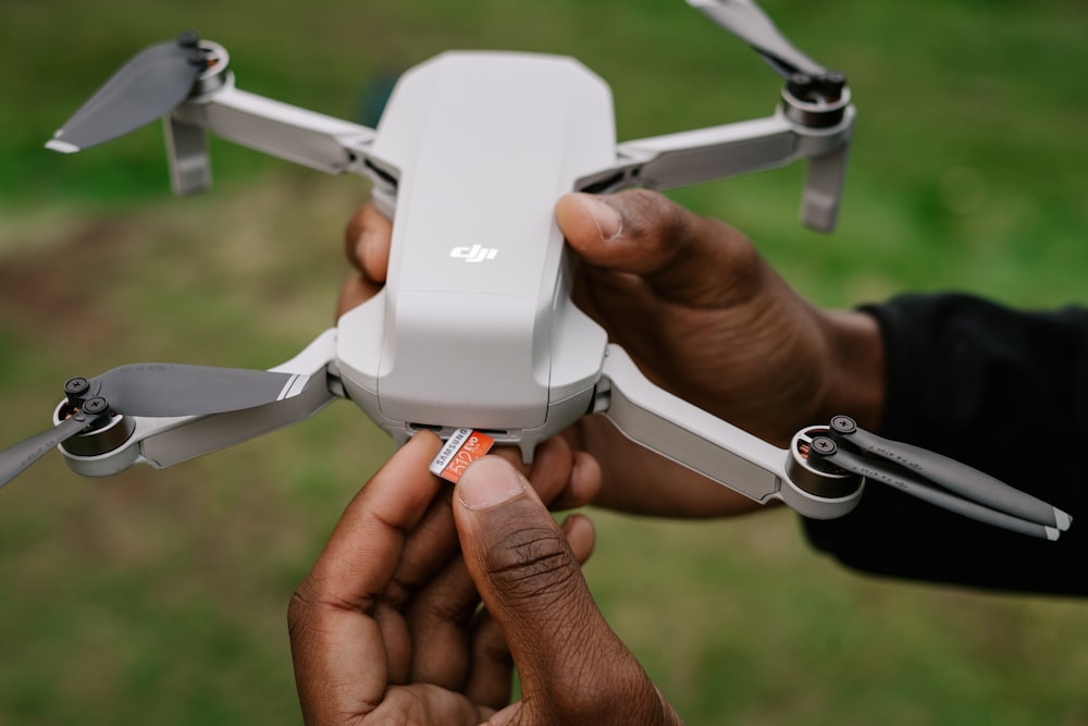 person holding white quadcopter drone
